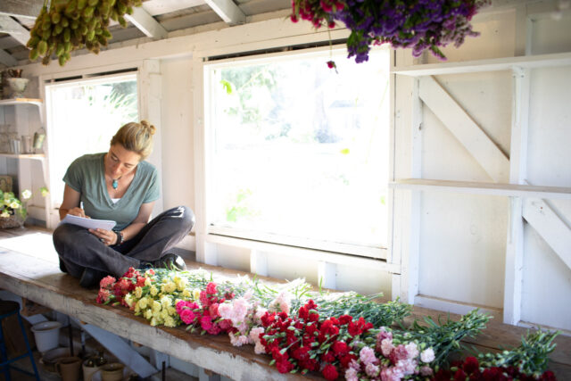 Erin Benzakein taking notes in the studio with bunches of carnations in front of her