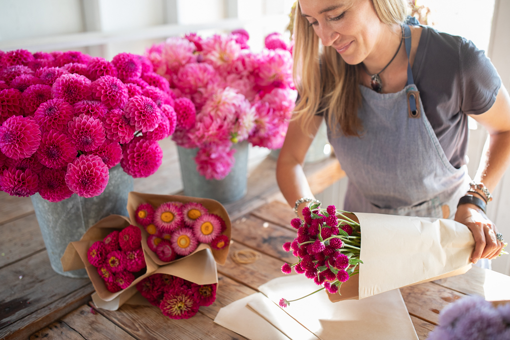 Erin Benzakein packaging bouquets of pink flowers into kraft paper sleeves in the Floret studio